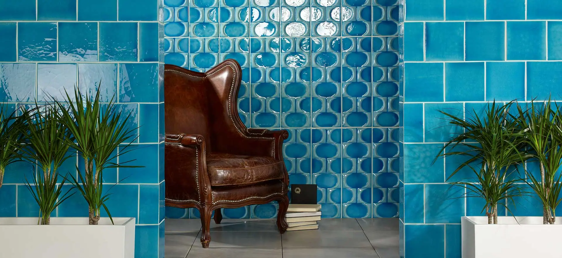 Blauwe mediterrane muurtegels met reliëf achter een leren fauteuil