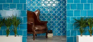 Blauwe mediterrane muurtegels met reliëf achter een leren fauteuil